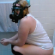 A fat, blonde girl wears a gas mask while taking a piss and shit sitting on a toilet. She tells us that she is protecting herself from the smell. Very subtle pooping sounds. Product not shown. Presented in 720P HD. About 4 minutes.